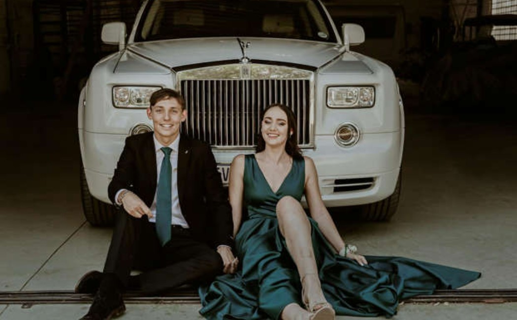 A young couple in formal prom attire sits in front of a luxury white car, smiling confidently.

Prom Night Rides captured in an elegant and stylish moment before the celebration.