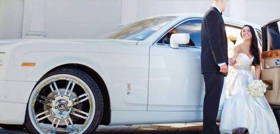 Bride stepping out of a luxury white car with the groom assisting her, showcasing elegant Wedding Transportation Services for a special day.